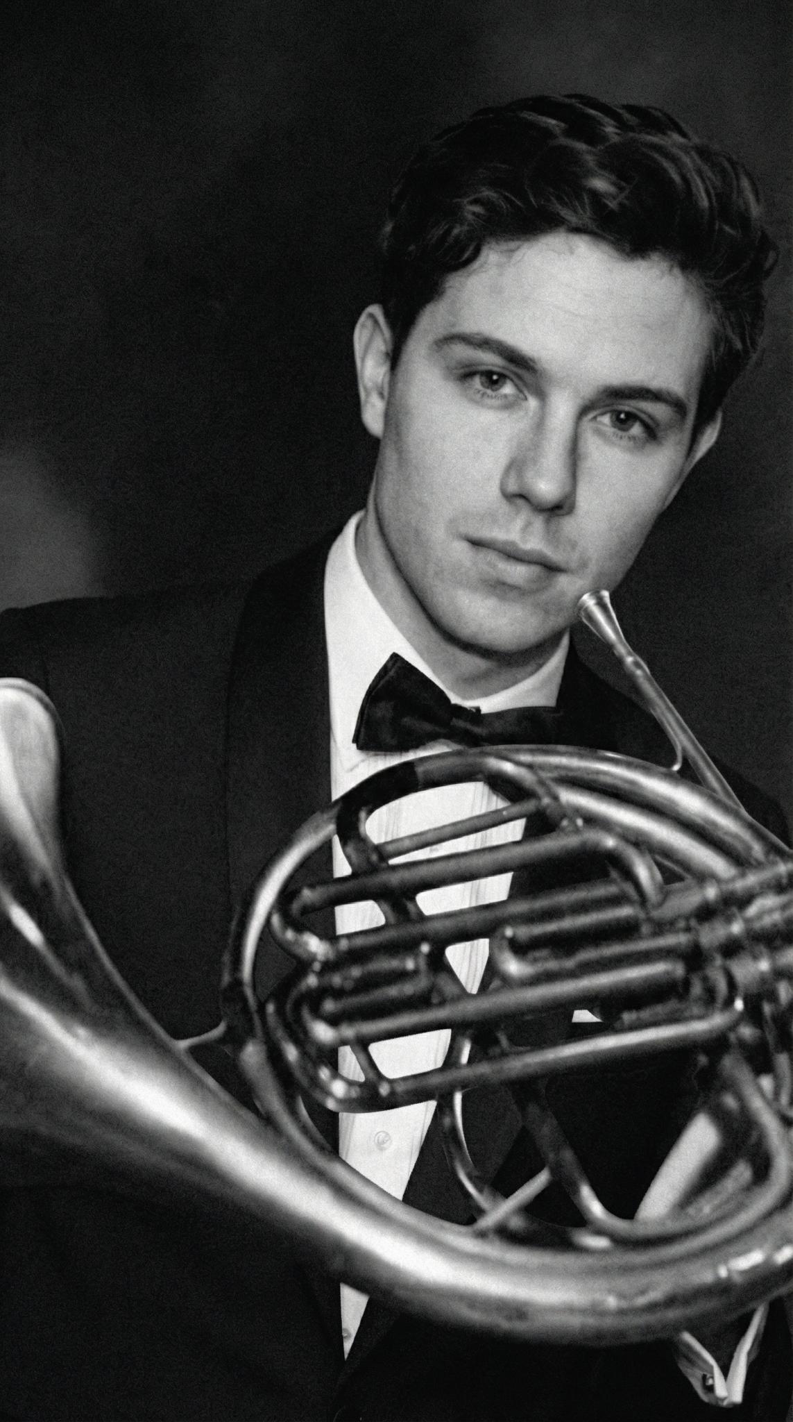 Black and white tuxedo portrait holding French horn