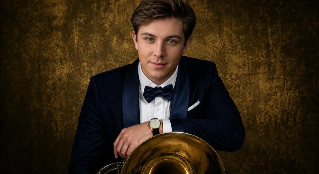 Trevor in a velvet tuxedo with arms crossed on the horn